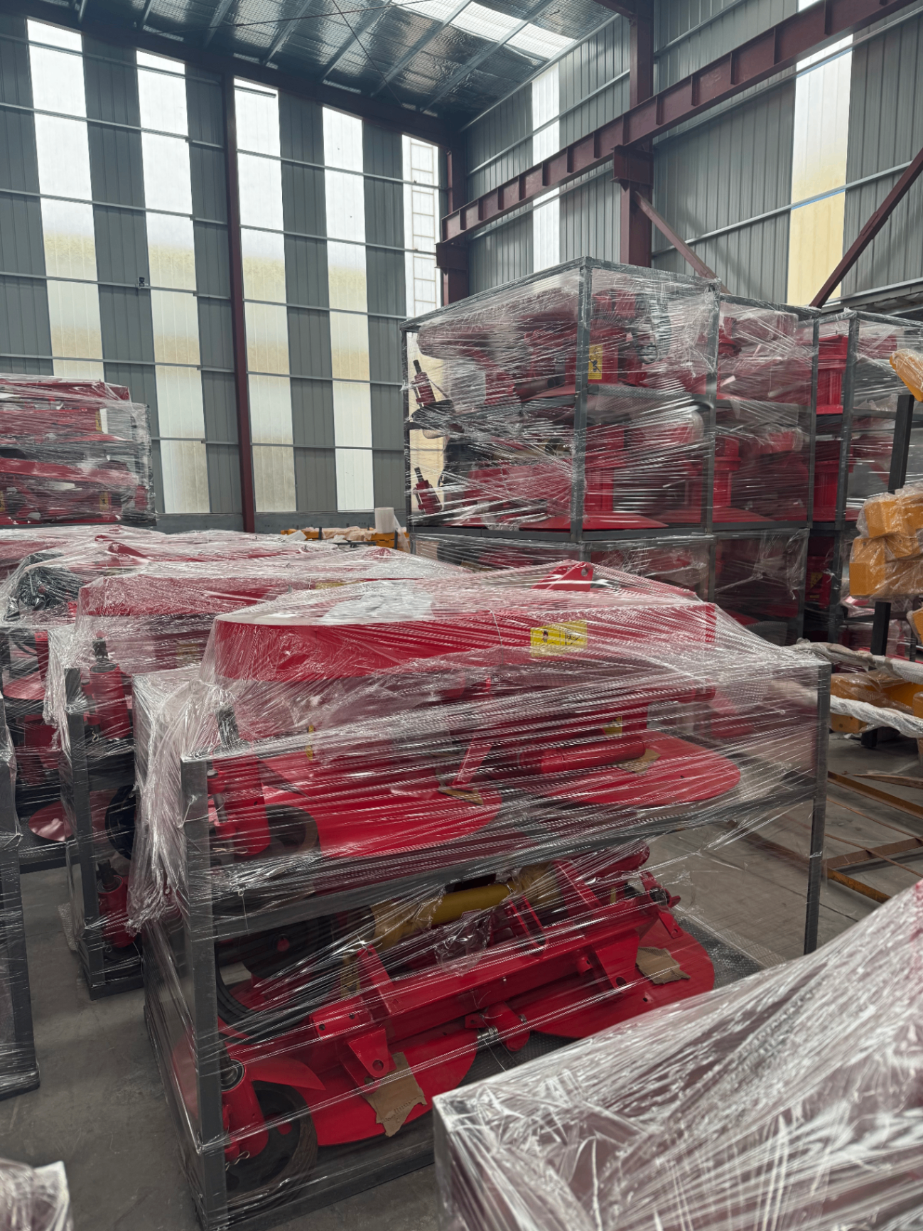 Multiple red rotary implements shrink-wrapped in steel frames for batch overseas shipment.