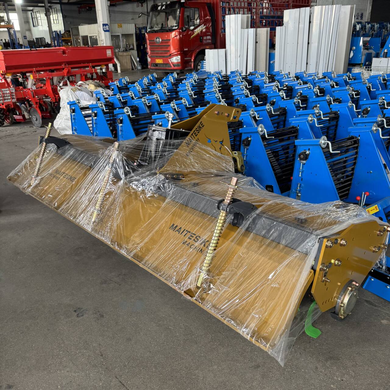 Maitesike-branded ridger wrapped and palletized alongside rows of finished planters.
