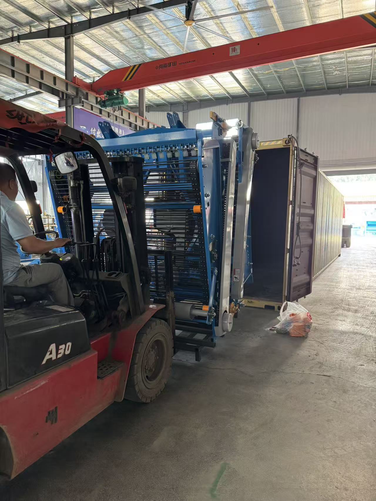 Forklift guiding a harvester upright into the container under the in-house 10t crane.